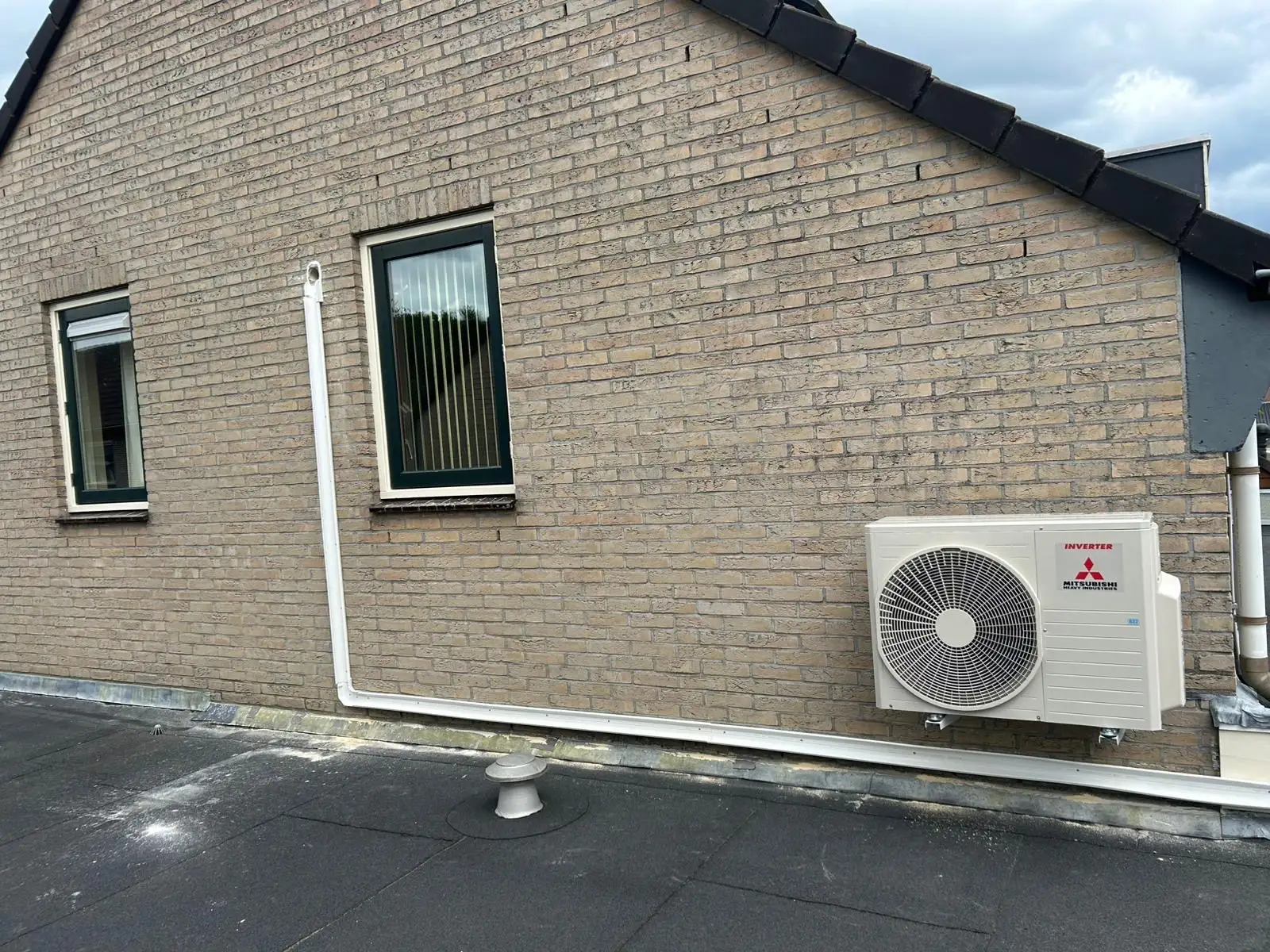 Mitsubishi Heavy Industries airco buitenunit op een plat dak met strak weggewerkt leidingwerk langs de gevel