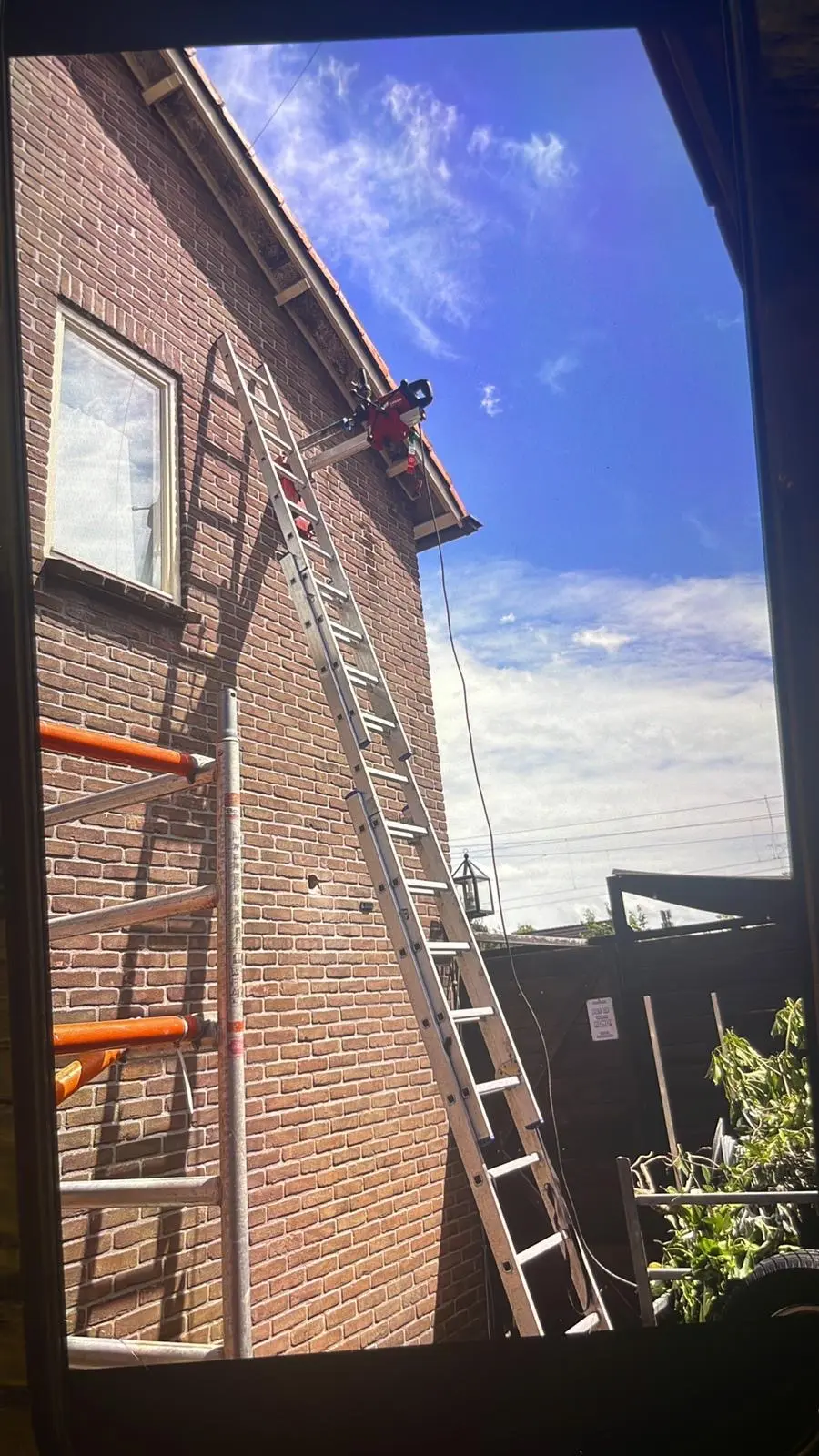 Diamantboorwerkzaamheden op hoogte met een ladder tegen een bakstenen gevel