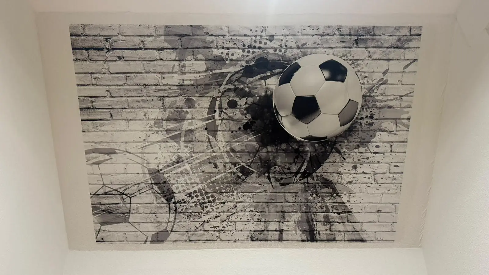 Strak aangebracht fotobehang met een voetbal op een gestucte wand in een kinderkamer