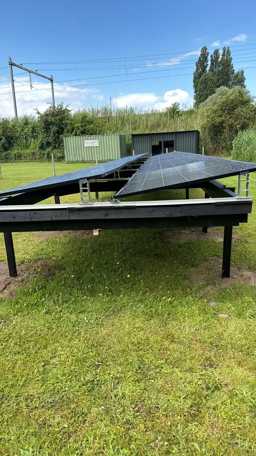 Zonnepanelen in een zwarte houten grondopstelling in een weiland