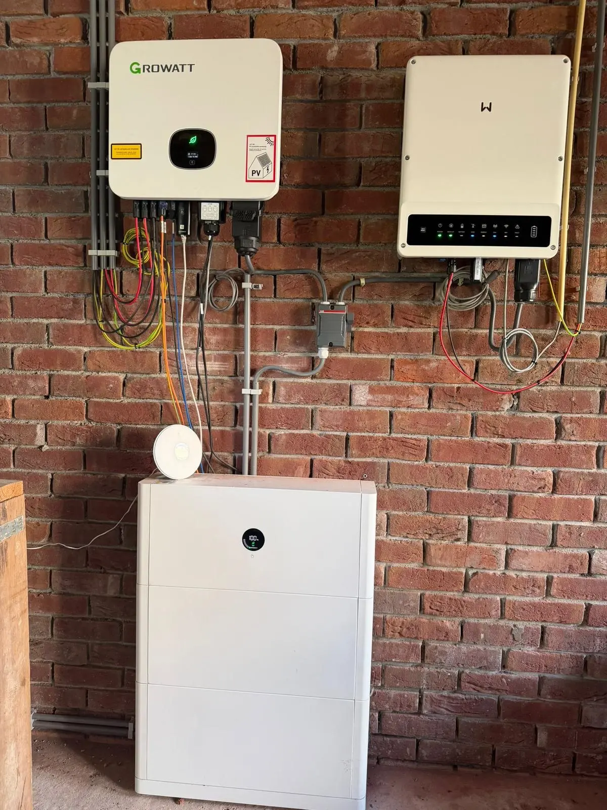 Growatt omvormer, batterij-omvormer en witte thuisbatterij gemonteerd aan een bakstenen muur